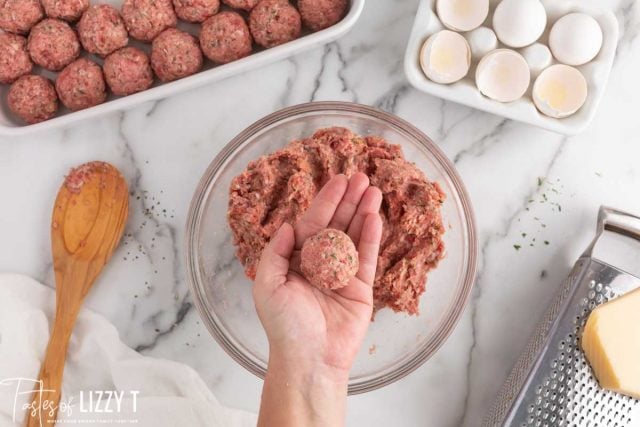 a hand holding a rolled meatball