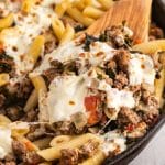 fresh mozzarella over italian sausage and pasta in a skillet