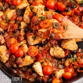 one skillet mediterranean chicken with a wooden spoon