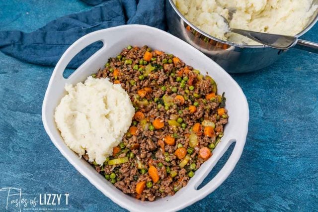 putting mashed potatoes over ground beef and vegetables