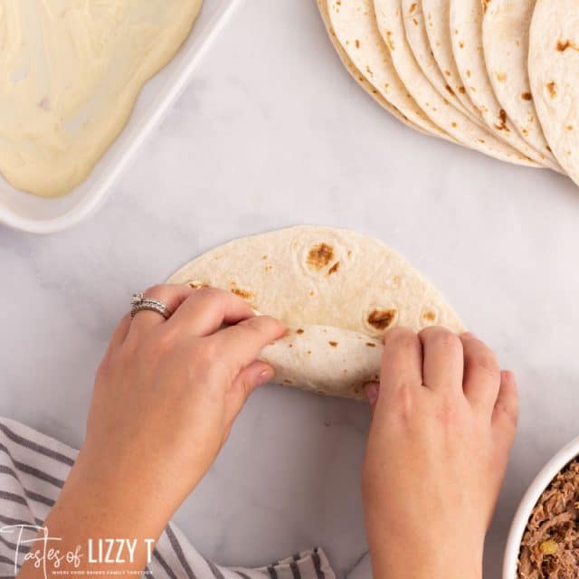 hands rolling enchiladas