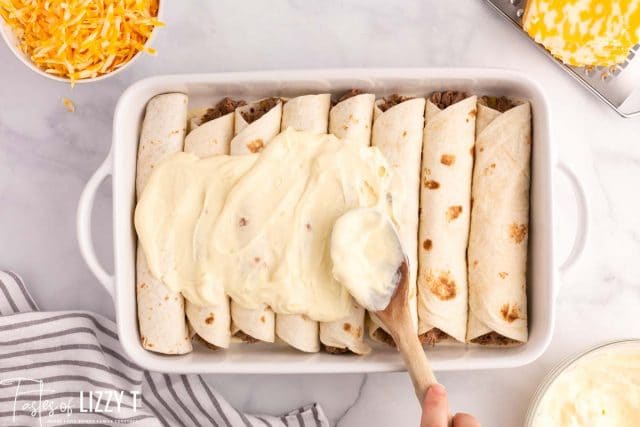 spreading creamy topping on roast beef enchiladas