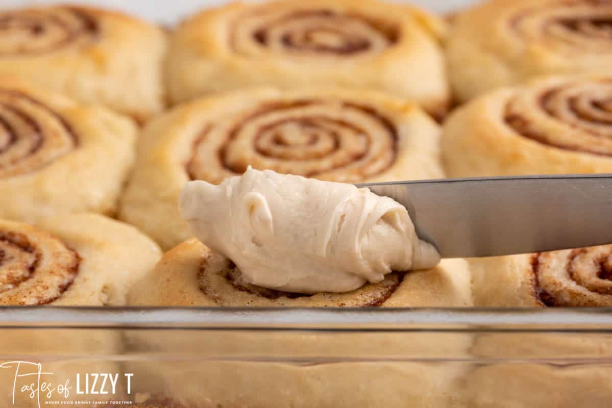 spreading icing on a cinnamon roll