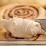 spreading icing on a cinnamon roll