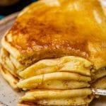 closeup of a fork cut into a stack of 4 pancakes