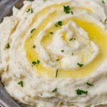 mashed potatoes in a bowl with butter and parsley on top