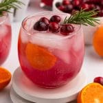 a glass of punch with cranberries and orange