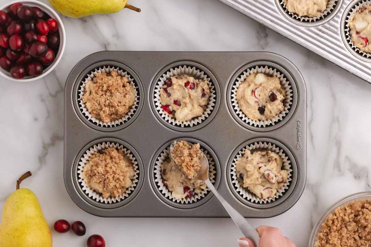 spooning streusel over muffins