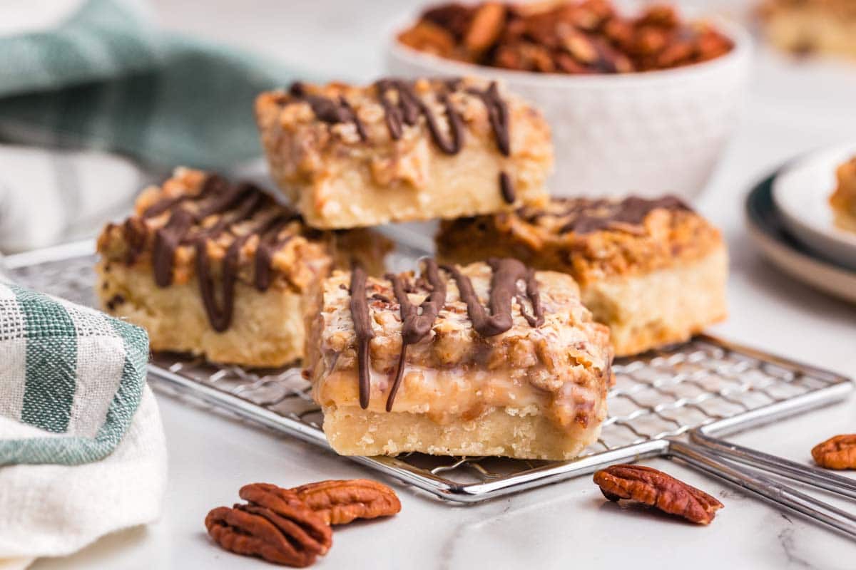 4 shortbread bars with pecans and chocolate drizzle on a table