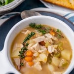 a bowl of chicken soup with potatoes and sprigs of thyme