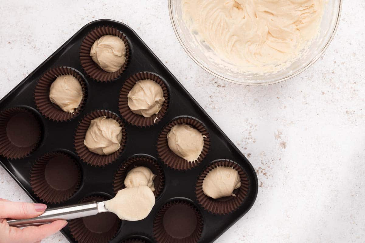 spoon scooping cupcake batter in a pan