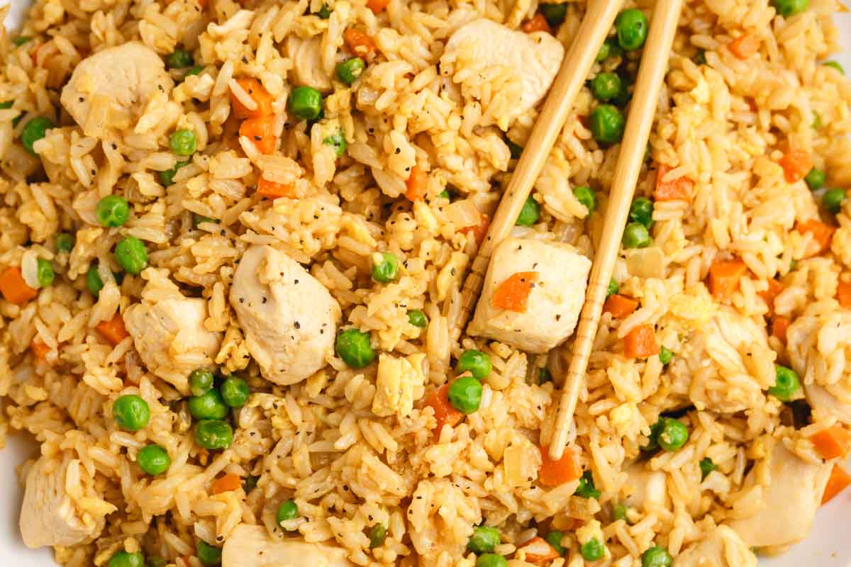 an overhead view of fried rice in a bowl with chopsticks