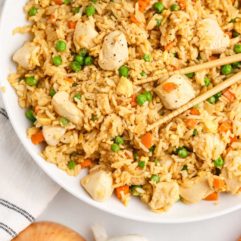 a plate of chicken fried rice with chopsticks