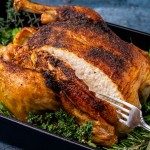 a golden brown roast chicken with a cut in it