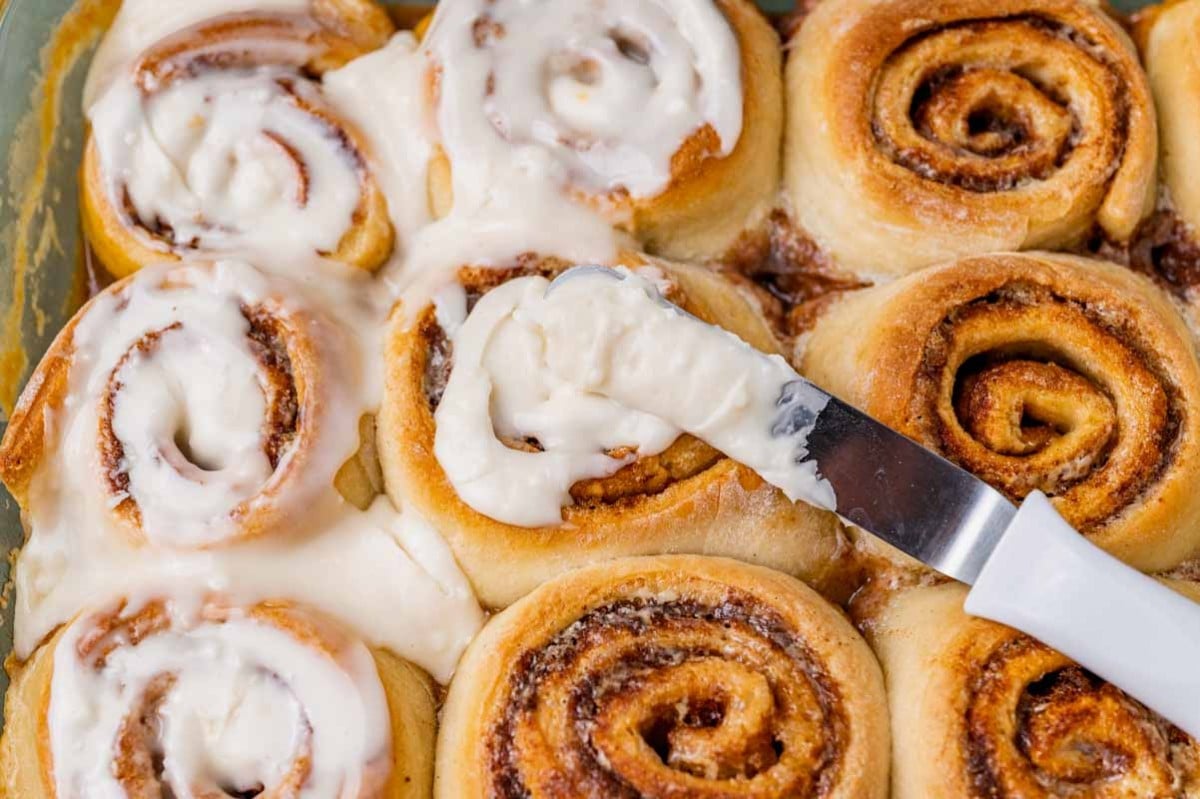 spreading icing on cinnamon rolls