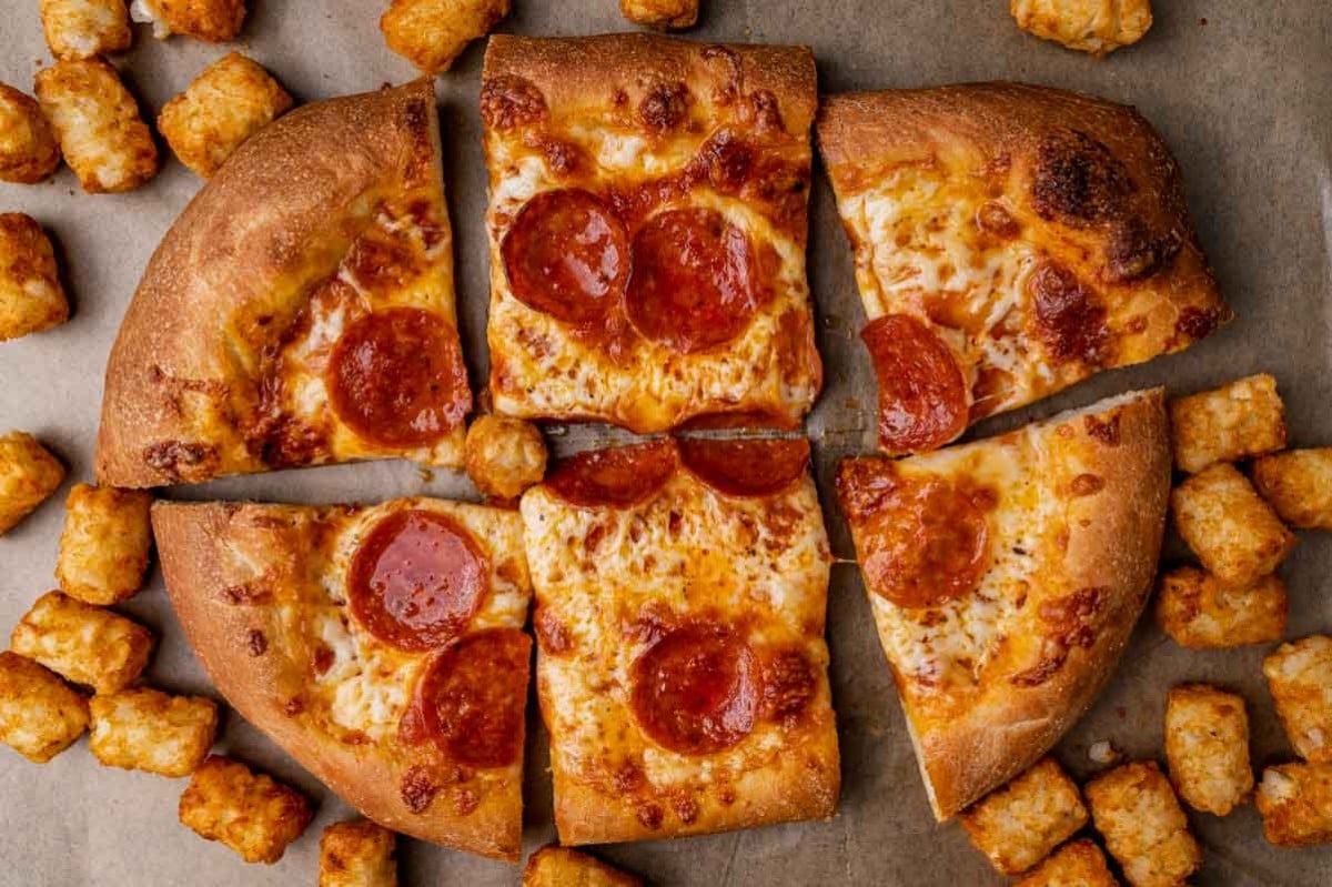 overhead shot of sliced pizza and tater tots