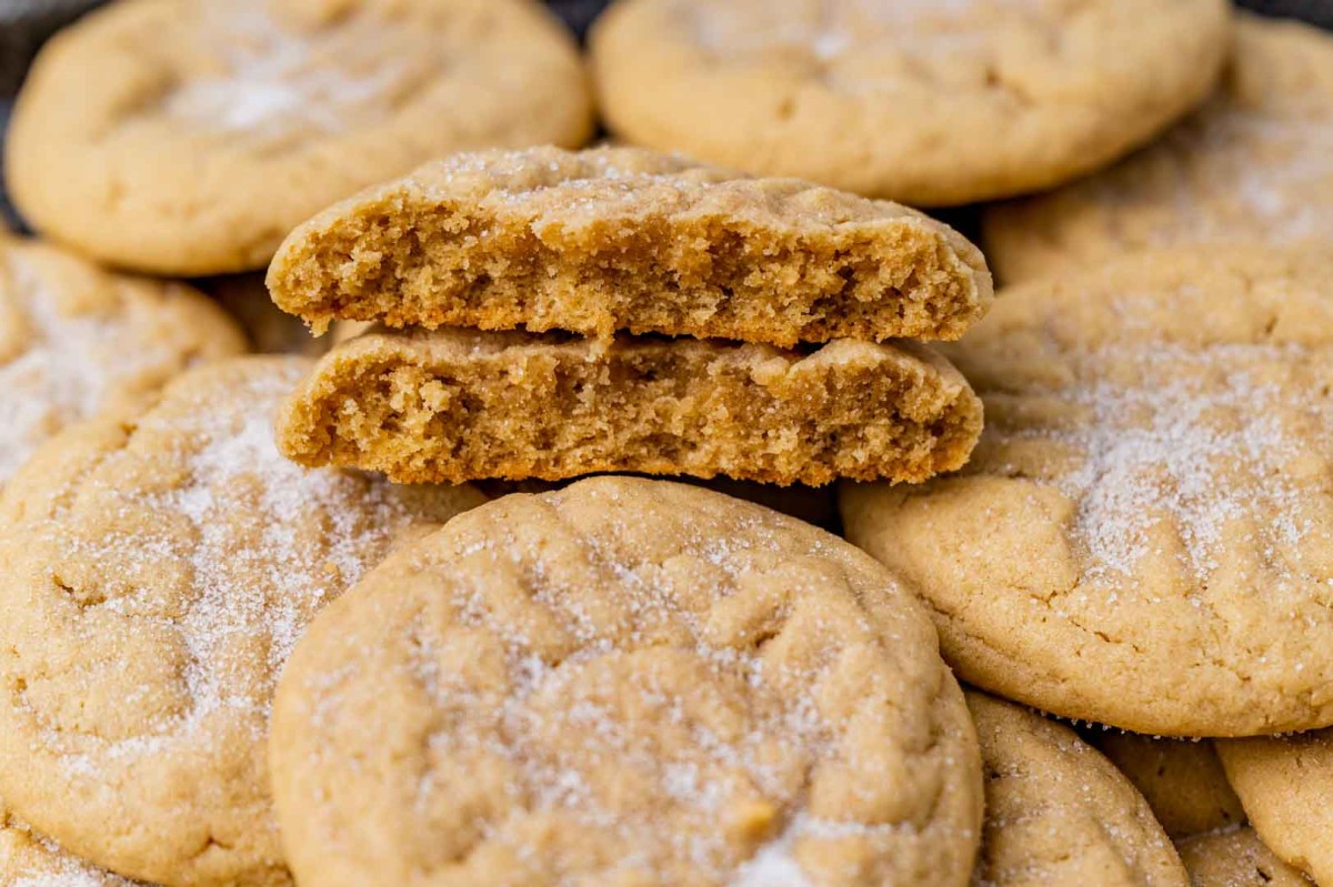 a peanut butter cookie broken in half on a pile of cookies