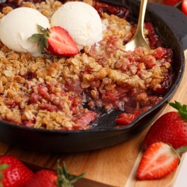 strawberry crisp in a skillet with a scooped out