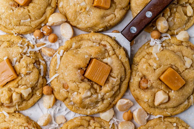 caramel topped coconut macadamia nut cookies on a spatula