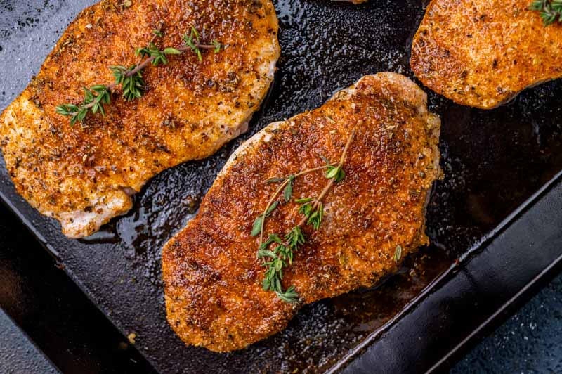 pork chops in a skillet with fresh thyme