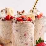 a full jar of overnight oats with strawberries and bananas with a spoon
