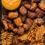 a chicken nugget with waffle fries on a baking pan