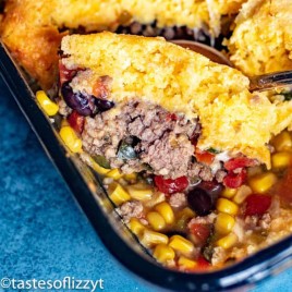 spoon going into beef tamale pie with cornbread on top