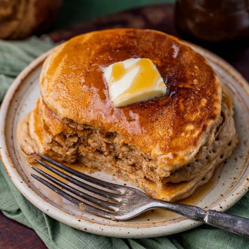 a stack of pancakes with one bite missing