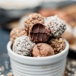 a bowl of chocolate truffles, one with a bite out of it