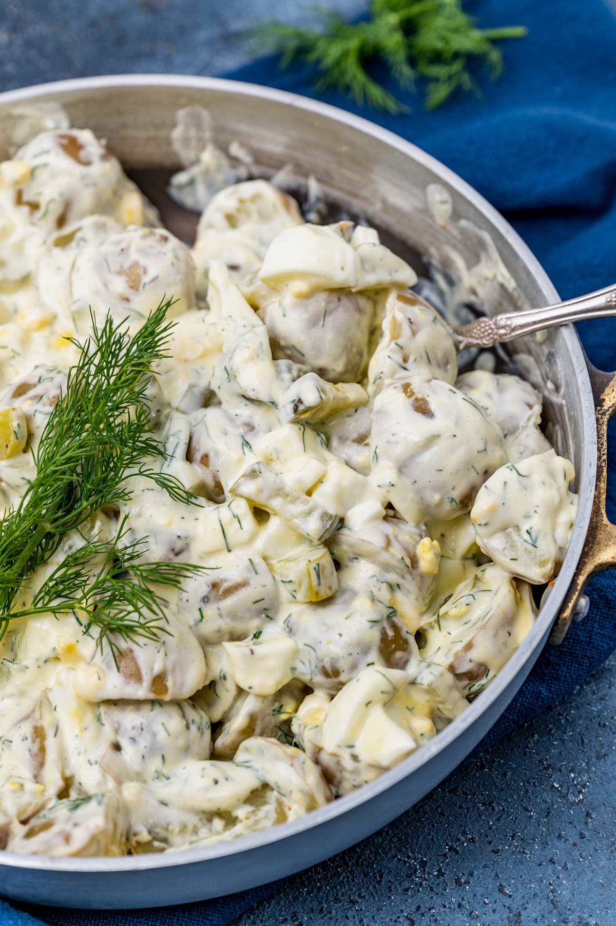 dill potato salad in a pan with a spoon