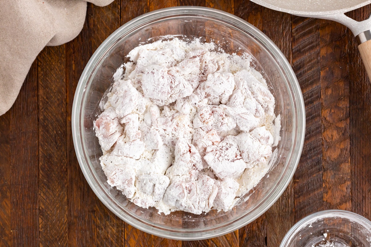 floured chicken pieces in a glass bowl