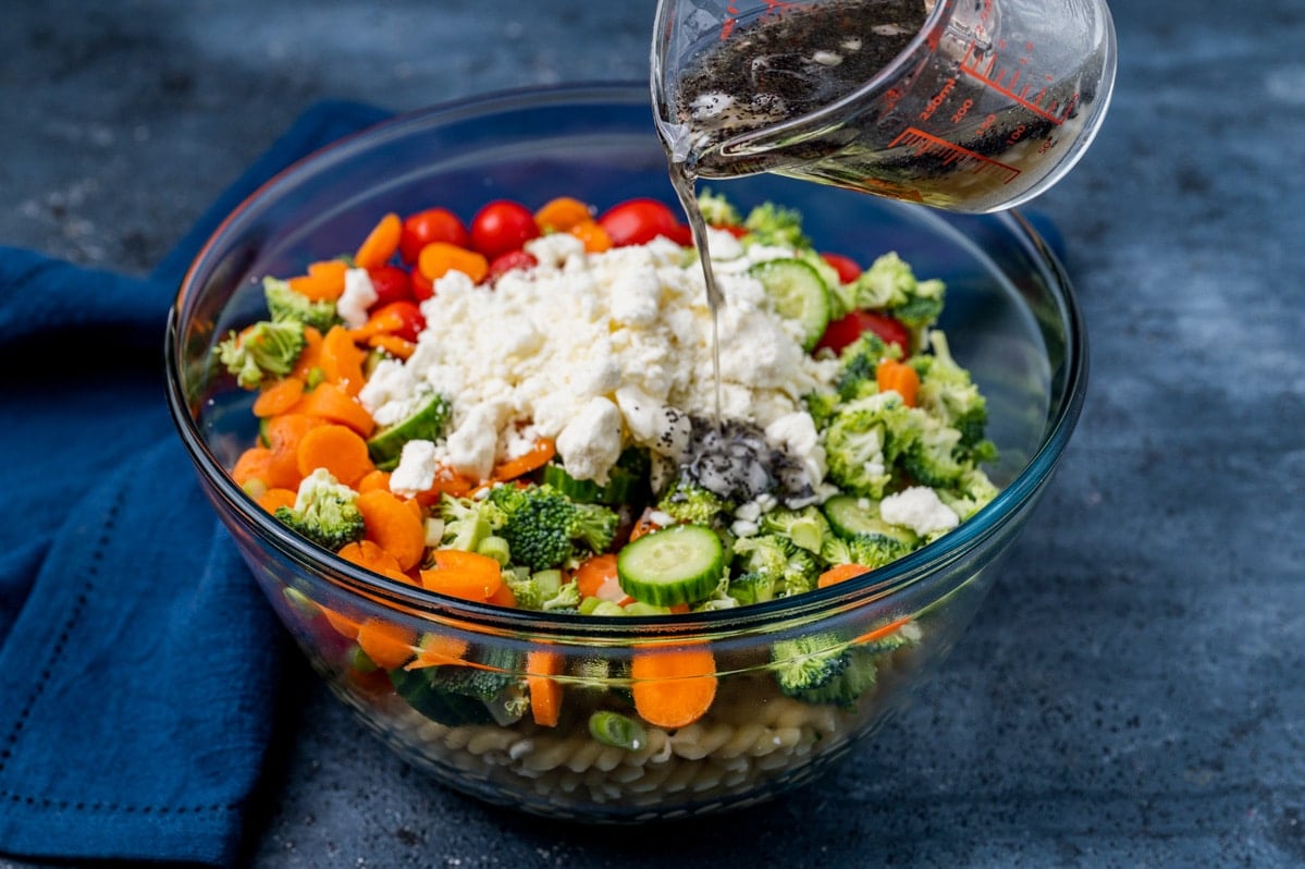 poppy seed dressing pouring over salad in a bowl