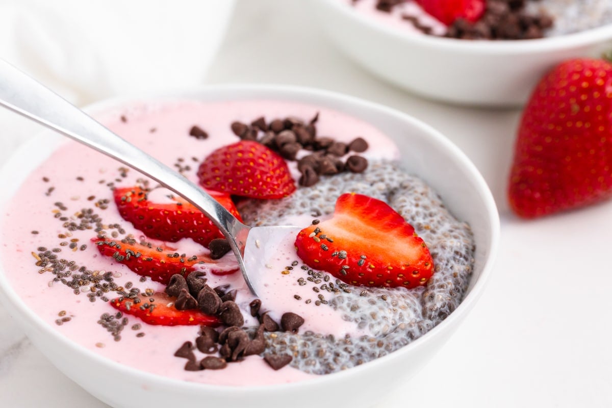 a spoon in a strawberry chia seed smoothie bowl