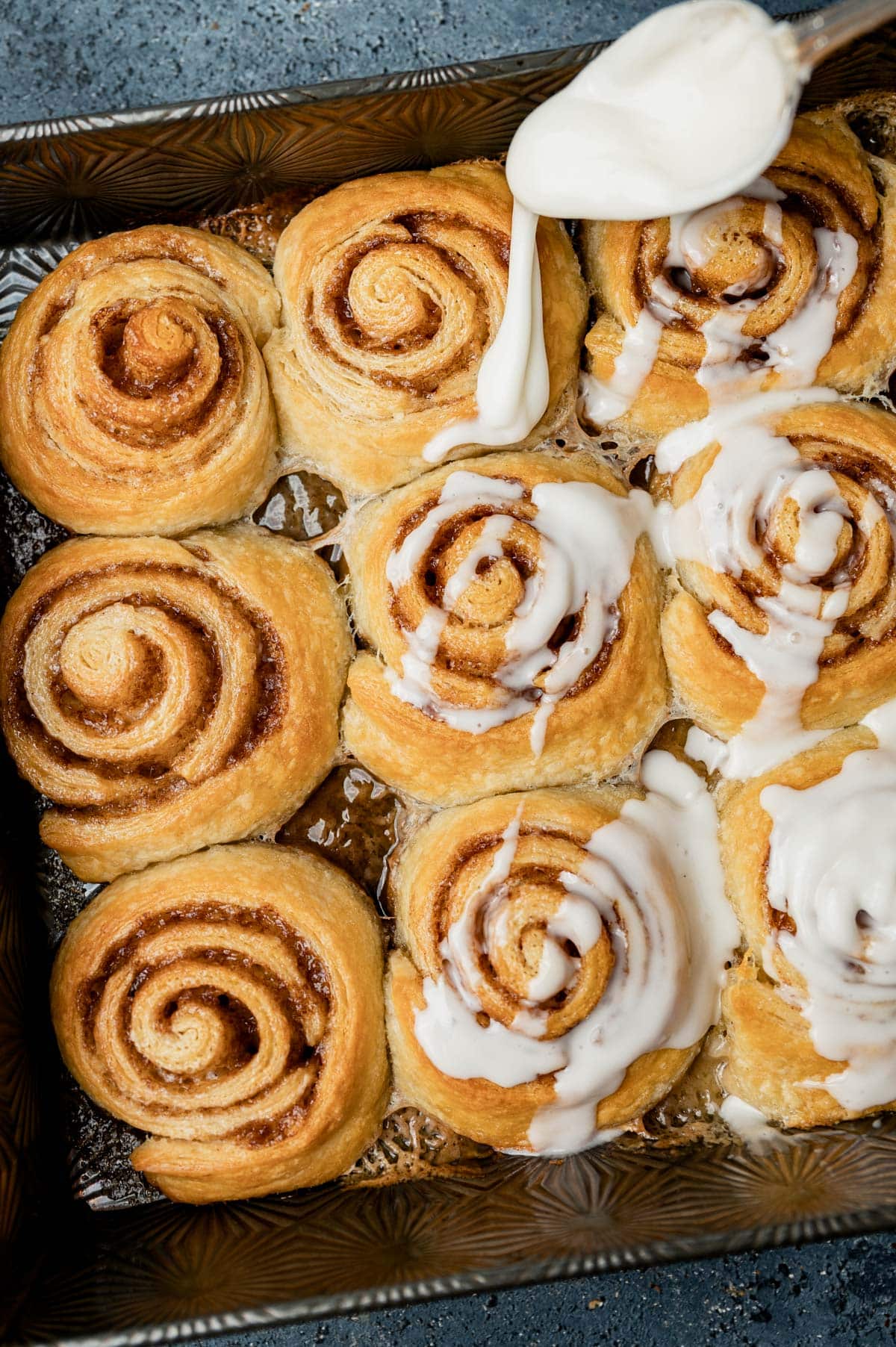 drizzing glaze on cinnamon rolls made from crescent dough