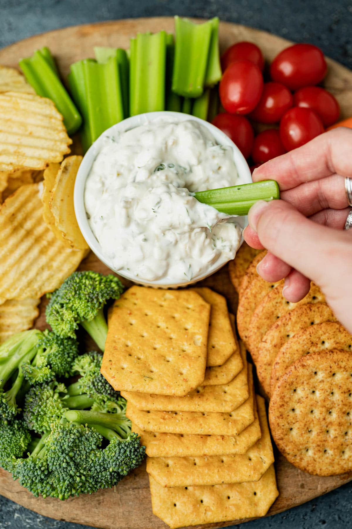 hand dipping celery into a bowl of dip