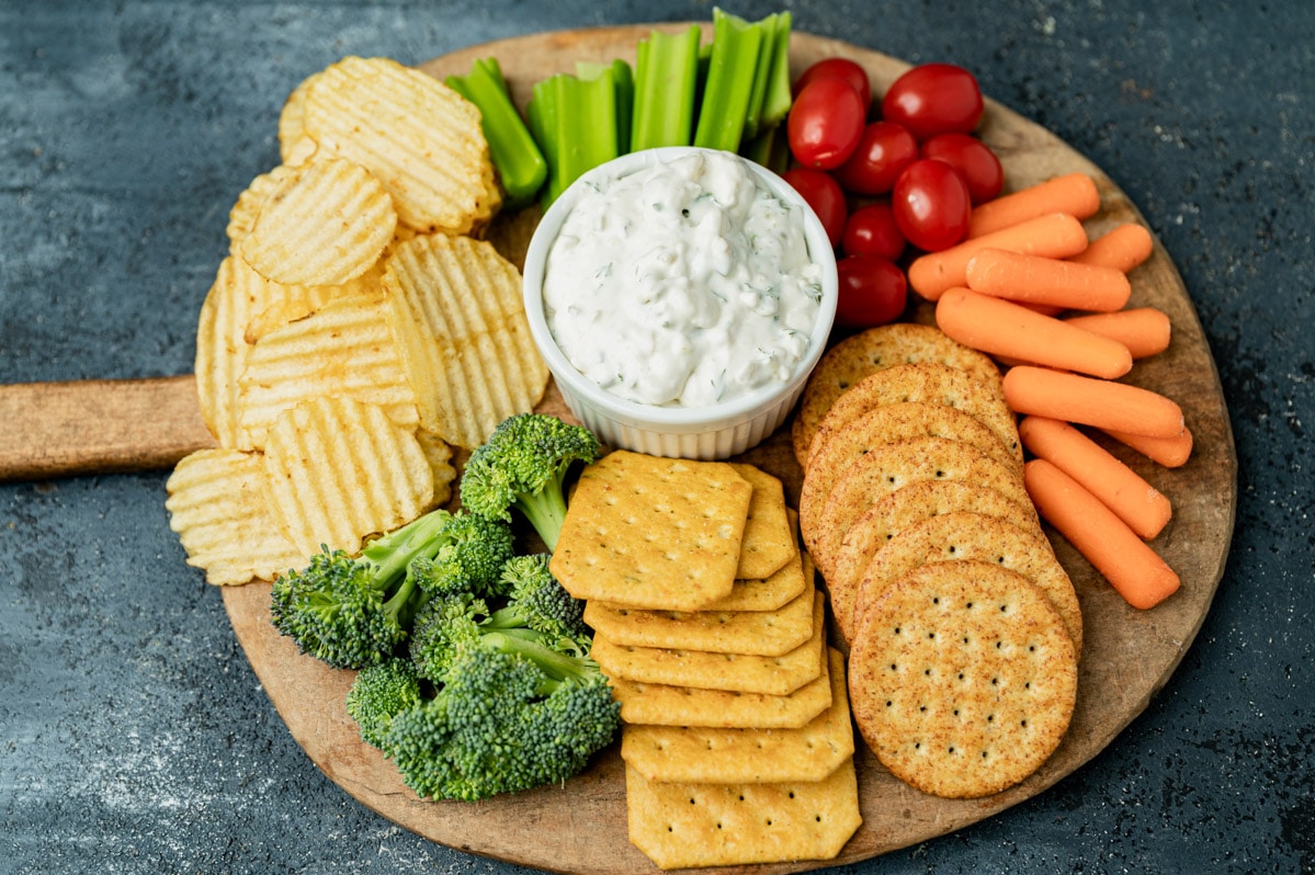 overhead view of a veggie and cracker board with dill pickle dip
