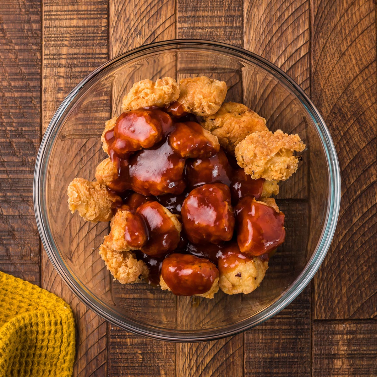 fried chicken in a bowl with honey sesame sauce over top