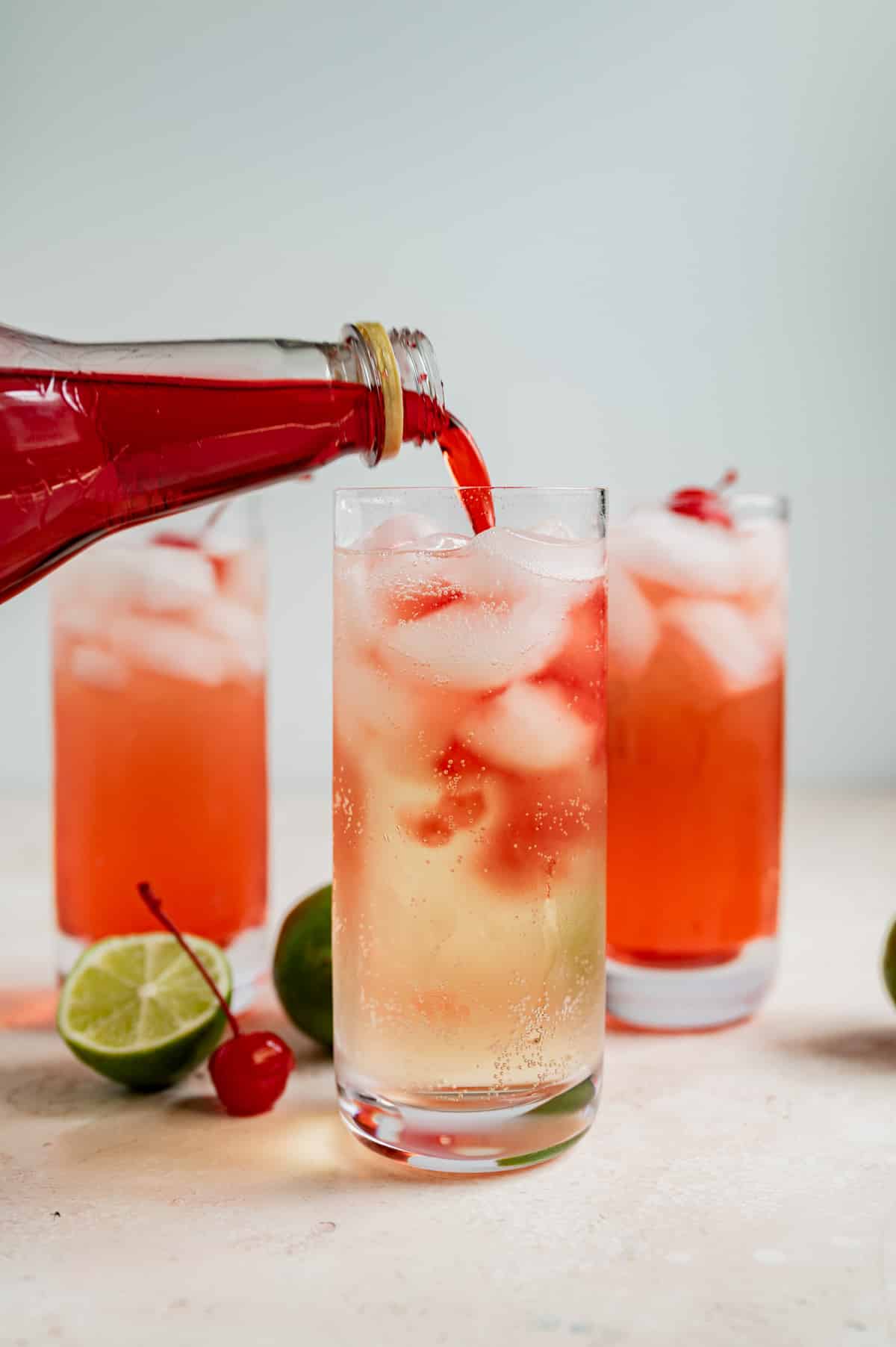 pouring grenadine syrup into a glass of ginger ale