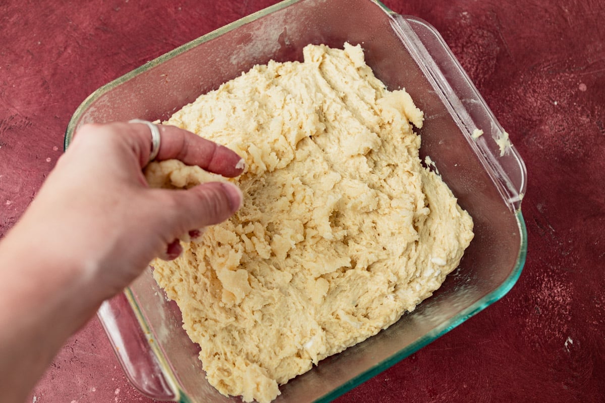 sprinkling streusel over shortcake in a pan