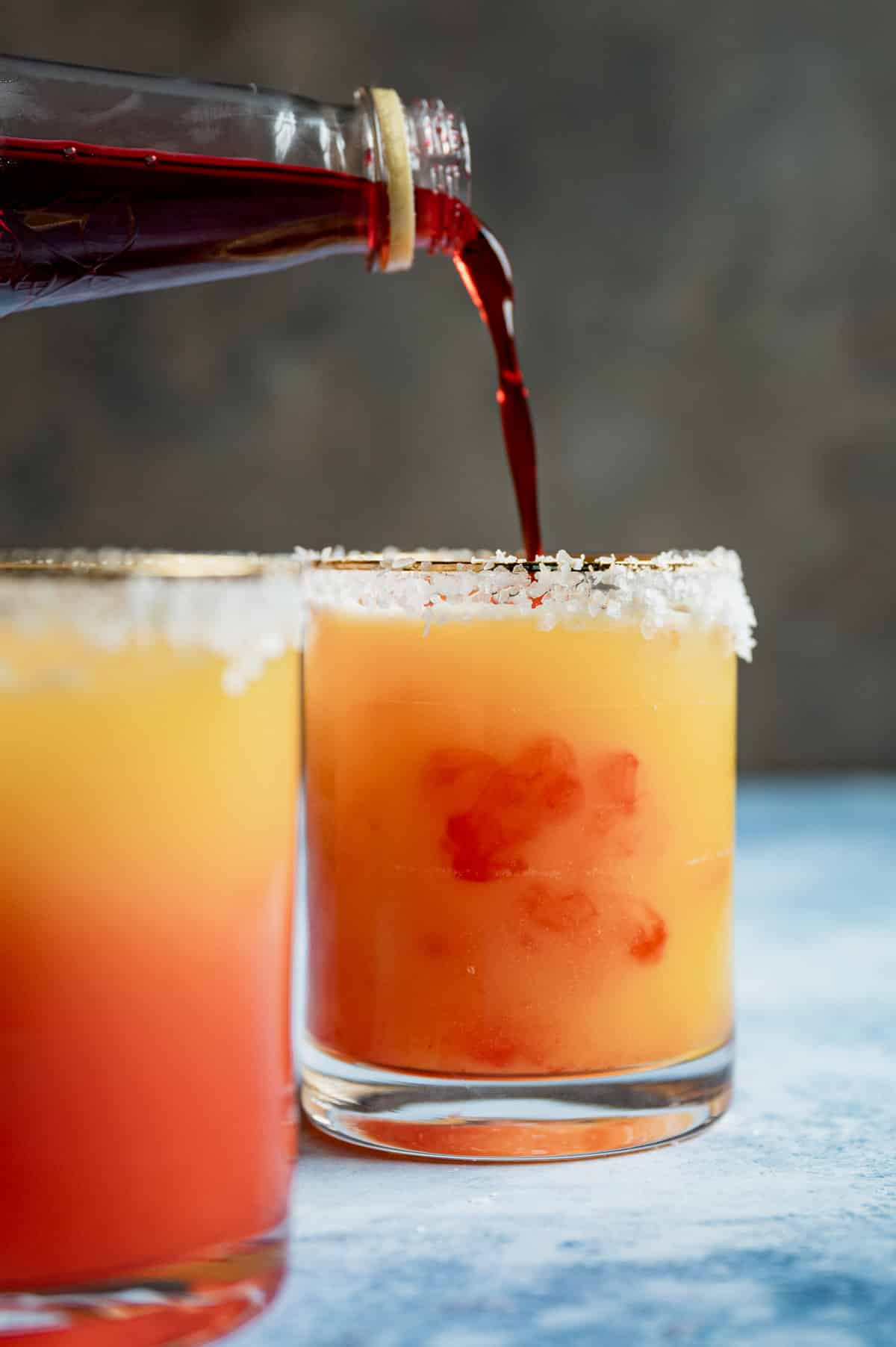 grenadine syrup pouring into a sunrise mocktail