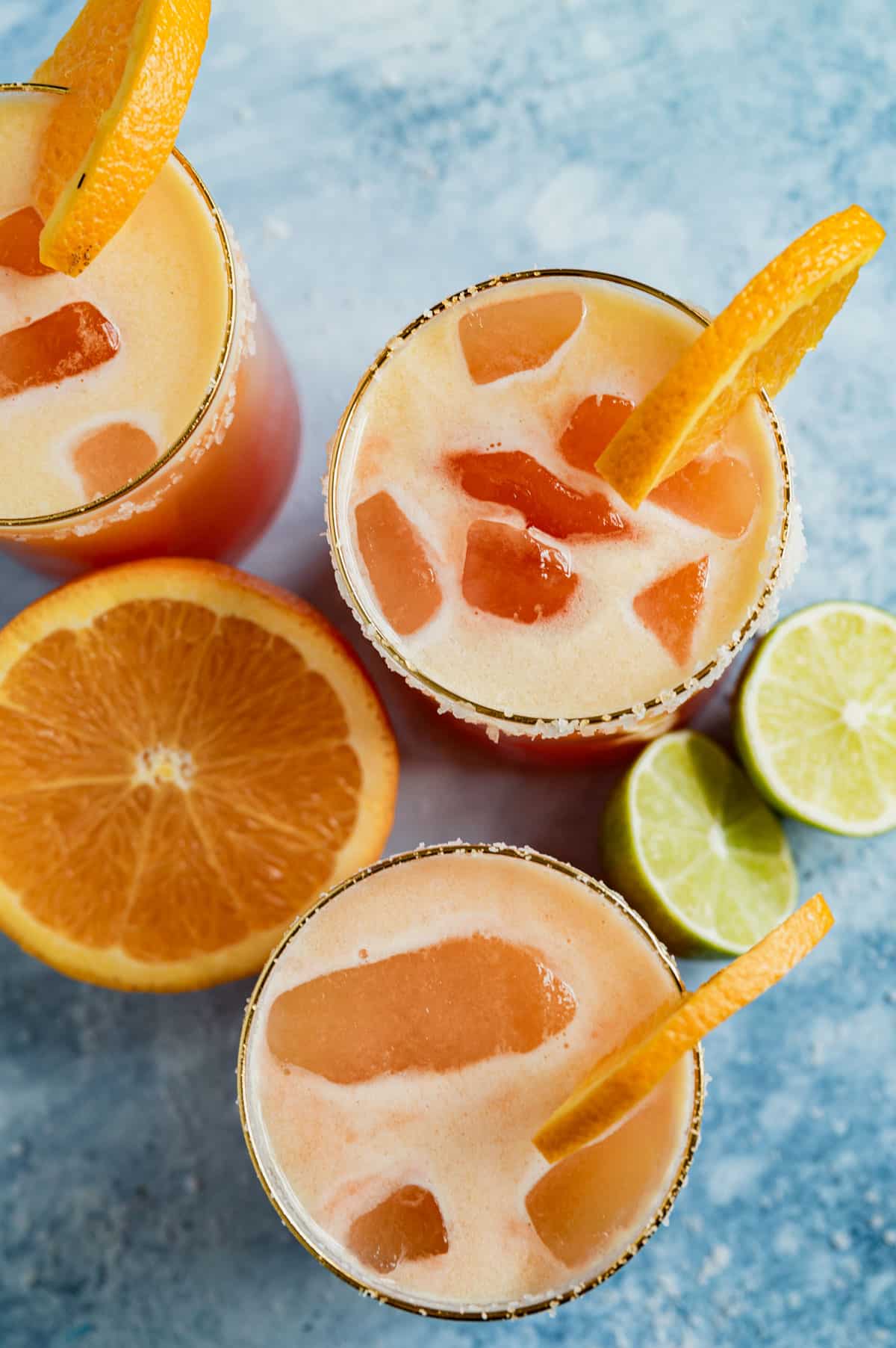 overhead view of 3 sunrise mocktails with orange