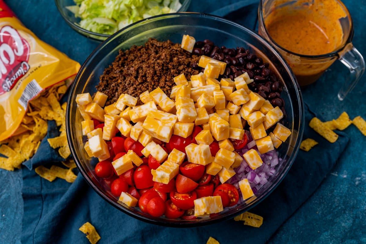 cheese, tomatoes, ground beef, beans and onions in a bowl