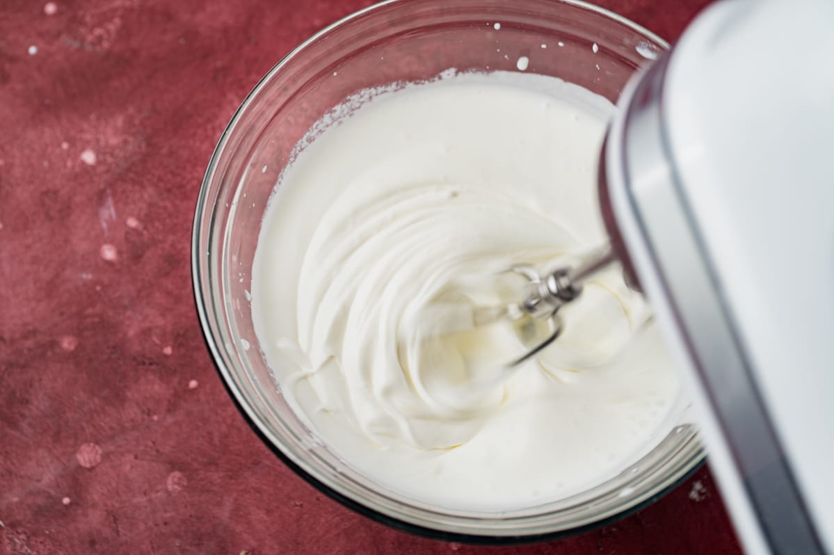 whipped cream in a mixing bowl with a mixer