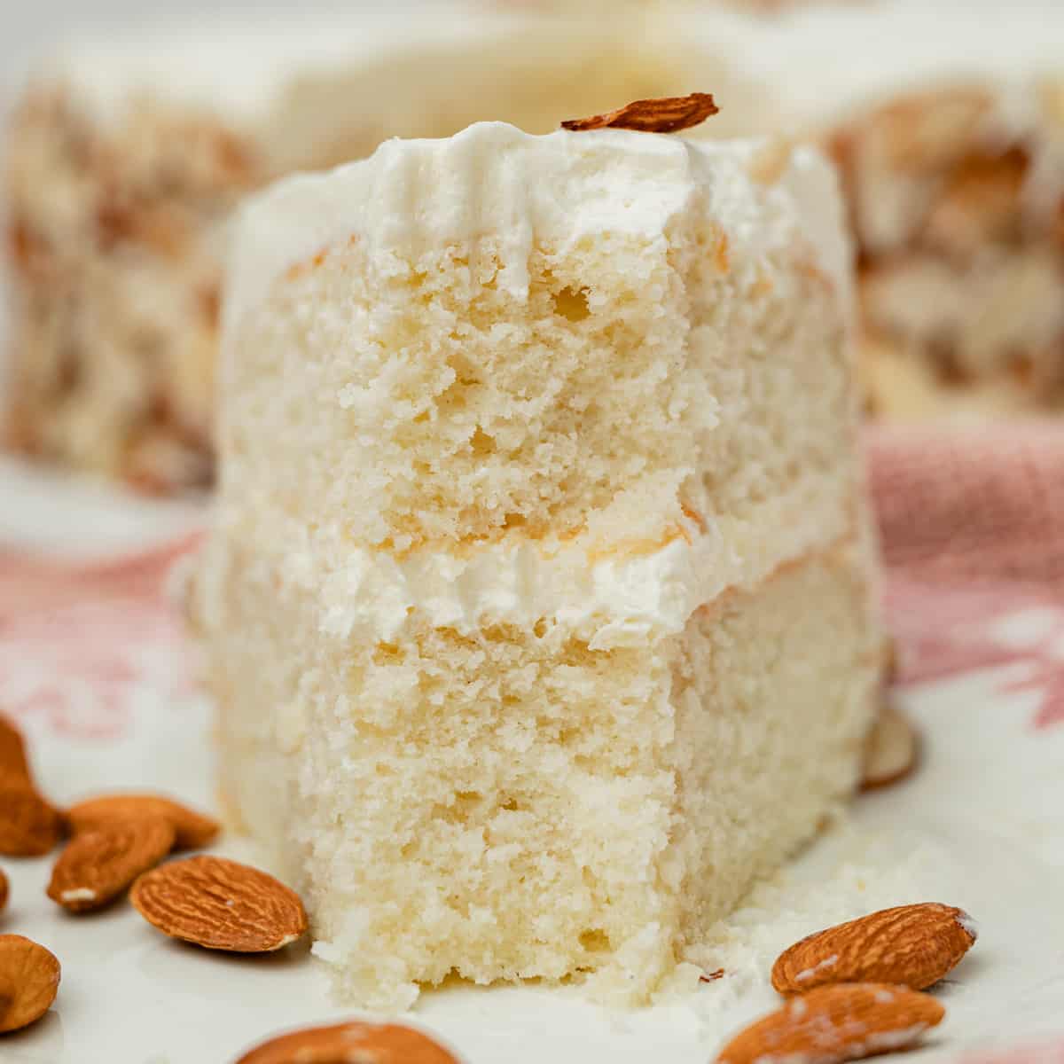 a slice of almond cream cake on a plate with a bite out
