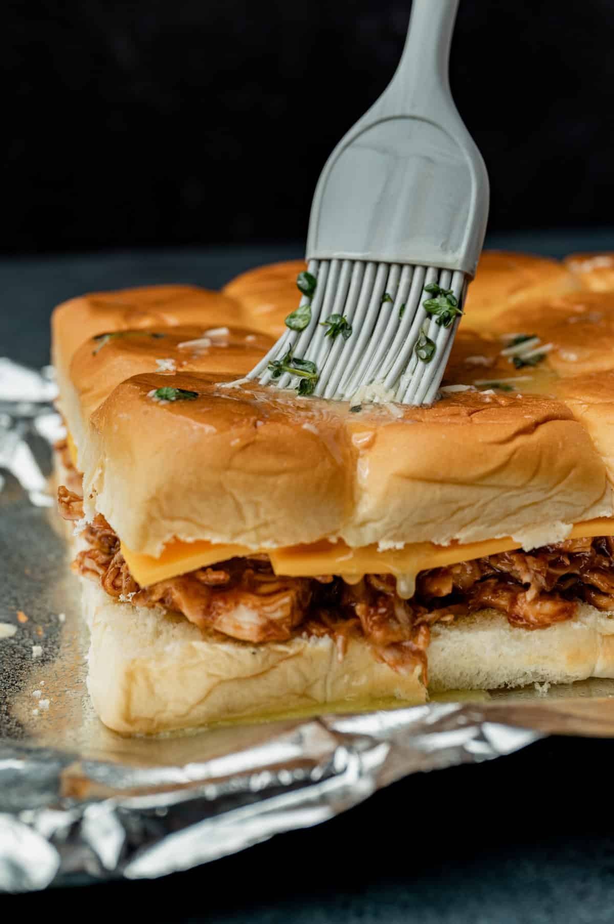 brushing butter on top of unbaked bbq chicken sliders