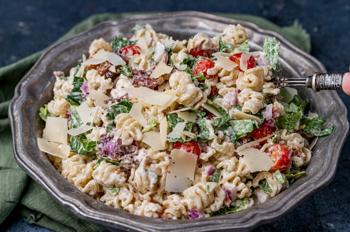 a bowl of blt pasta salad with parmesan shavings on top