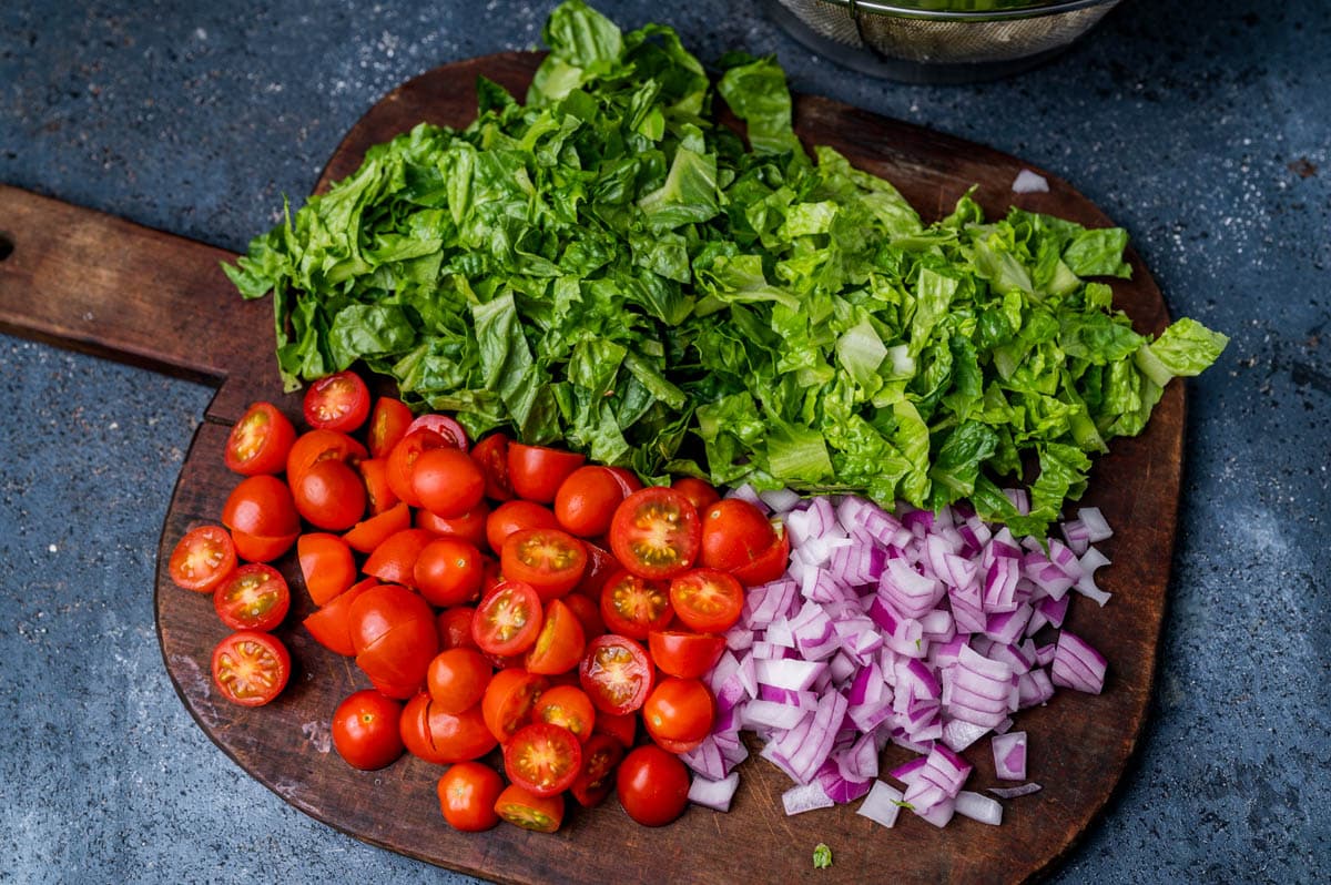 lettuce, tomato and onion on a cutting board