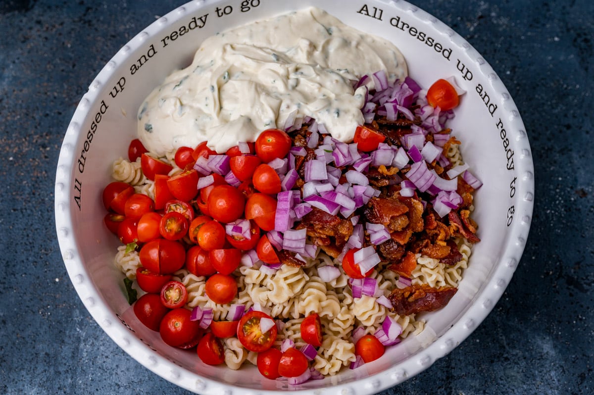 tomatoes, onion, bacon, dressing and pasta in a bowl