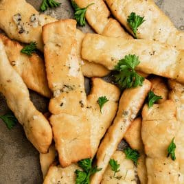 closeup of buttery breadsticks on parchment paper