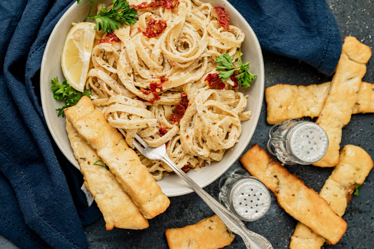 overhead view of a bowl of pasta with breadsticks